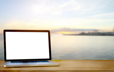 Laptop on wood table with blurred Twilight sea background. For Product display montage. Beach in summer Concept.