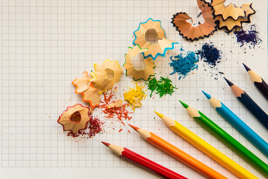 Multicolored pencil set and pencil shavings on a white squared paper background