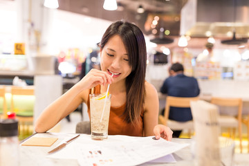 Woman enjoy soft drink and choosing on menu in restaurant