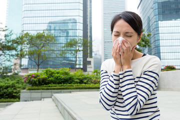 Woman sneezing at outdoor