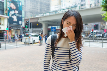Woman sneezing in Hong Kong city