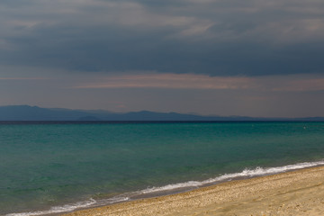 cloudy evening sky on the shore of an undulating turquoise sea in the spring of April.