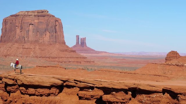 Man sitting on horse at the edge of a cliff in Monument Valley