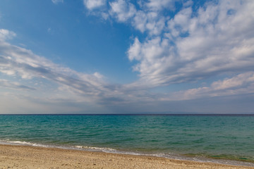 cloudy evening sky on the shore of an undulating turquoise sea in the spring of April.
