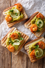 Tasty toast with guacamole, prawns and lime close-up. vertical top view