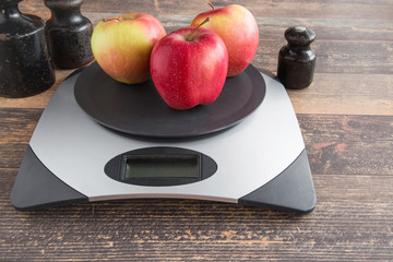 Apples on the weighing scales on the table in the kitchen. Healthy eating and lifestyle. 