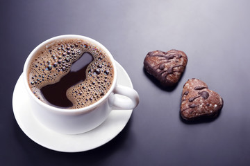 white cup of black coffee with biscuits on a dark background