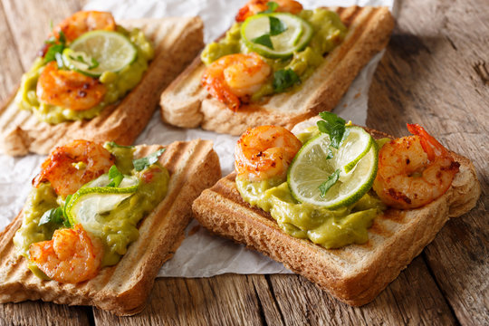 Delicious sandwiches with guacamole, shrimps and lime close-up. horizontal