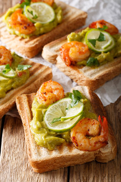 Toast with guacamole and shrimps close-up. vertical