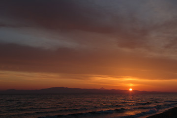 Fototapeta na wymiar Spring orange dawn on the shore of the calm sea during the tide.