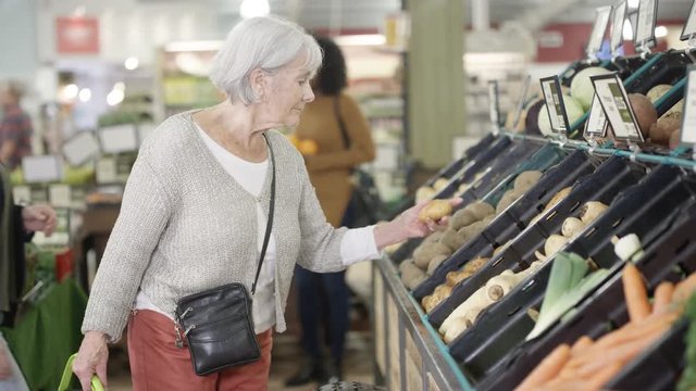  Cheerful senior lady shopping for groceries in the supermarket