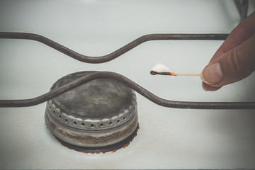 Hand ignited a match at the old gas stove for cooking. Vintage style.