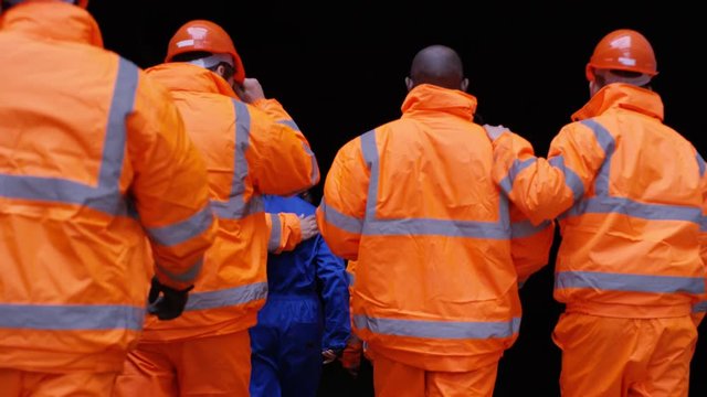  Workers at a fuel plant walking into darkness & preparing to go underground