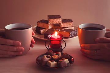 Man and woman enjoying coffee and sweets by candlelight and lovely conversations in the romantic evening atmosphere. 