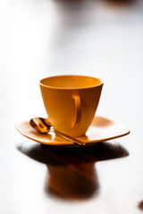 Cream (beige) Cup for coffee standing on a black table in the backlight.