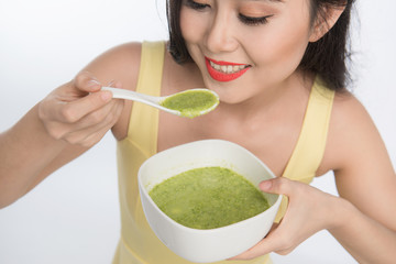 Portrait of asian woman eating/holding a plate of green vegetables soup