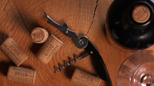 Background of used wine corks, wine bottle, corkscrew and glass.