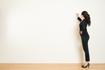Business woman writing something on white wall