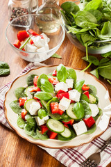 Fresh spinach salad with feta, cucumber and red paprika on a pla