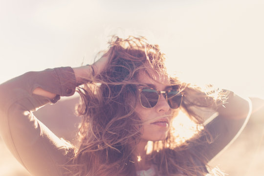 Girl modeling in thought at sunseT. Shot in Joshua Tree California at sunset, model wearing sunglasses with wind in hair looking straight ahead.  