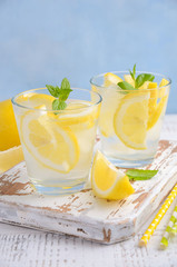 Fototapeta premium Cold refreshing summer drink with lemon and mint on wooden background. Selective focus, copy space.