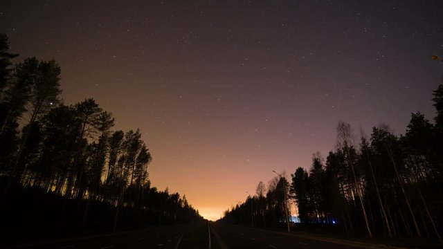 Timelapse. Night view on the forest highway, night sky, view on the stars, cars lights on the road. 4k footage. Long exposure.
