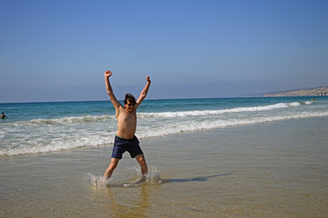 Happy tourist man jumping high on the beach and enjoying holiday in San Diego, California, USA