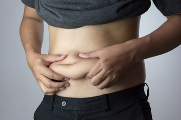 A young guy with a fat belly on a white background. / Concept for weight control and health care.