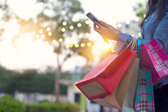 Woman using smartphone with shopping bags in hands