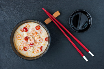 Asian noodle soup with seafood in ceramic bowl and chopsticks on dark  background with copy space
