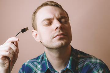 Young man with computer cable in his hand. Selective focus.