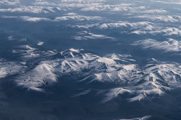 Fototapeta premium View from airplane on Earth surface - snow-capped mountains.