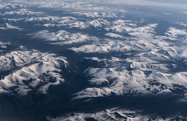 Fototapeta premium View from airplane on Earth surface - snow-capped mountains.