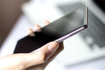 Hand holding mobile smartphone with blank screen.