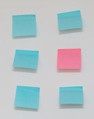 Single pink post it note in sea of blue post it notes