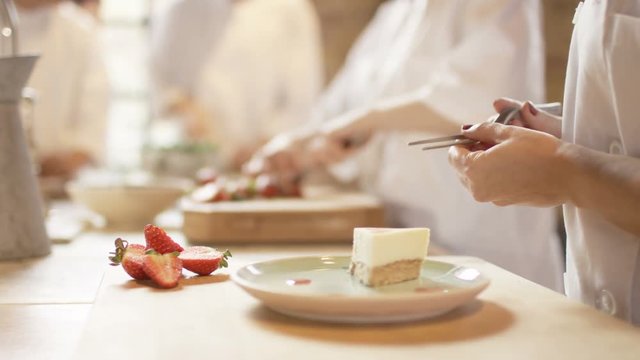  Young chef in professional kitchen gives finishing touches to dessert