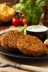Serving of falafel and chips served on a black plate with sauce.