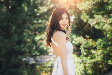 Beautiful brunette bride in the rays of the sun. Bride looking at the camera.