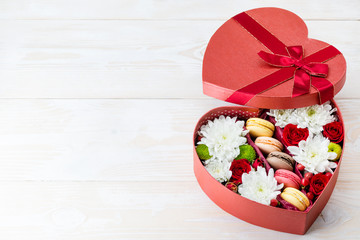 Box of flowers and macaroons heart on a wooden table. Copy space