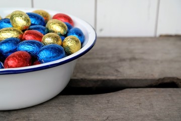 chocolate Easter eggs, red, blue and yellow, together in a enamel bowl, taken from above