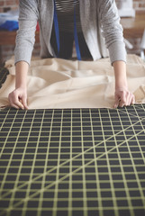 Tailor measuring fabric on the table .