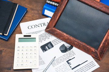 Obraz premium Close-up top view of contract, calculator, business charts and notebooks on wooden table