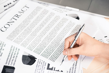cropped view of businesswoman signing contract documents sitting at table