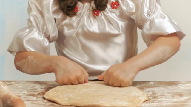 Girl hands knead the dough on the table.