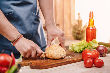 man making burgers and cutting red tomatoes outdoors