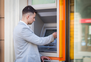young business man inserting credit card to atm outdoor