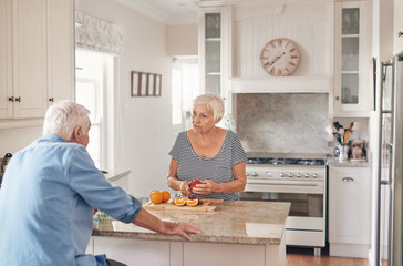Senior couple talking together while preparing breakfast in their kitchen