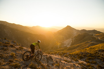 Cyclist man riding mountain bike at sunset