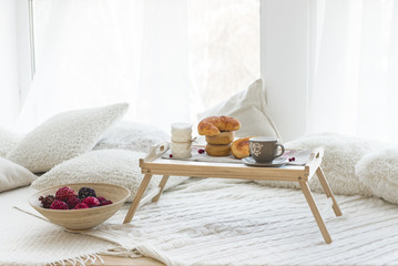 morning french breakfast with tea or coffee and bakery on the bed table near window 