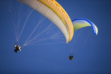 Two paragliders flying over mountains.